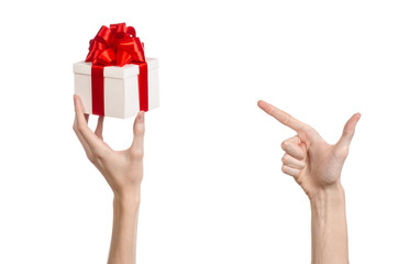 hand holding a gift wrapped in white box with red ribbon and bow