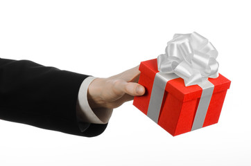 man in a black suit holding gift wrapped in red box