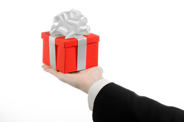 man in a black suit holding gift wrapped in red box