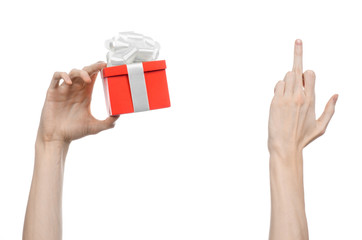 hand holding a gift wrapped in red box with white ribbon and bow