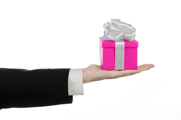 hand holding gift wrapped in pink box with white ribbon and bow