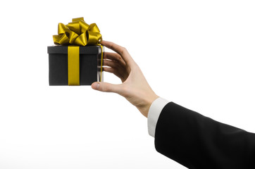 man in a black suit holding gift packaged in a black box