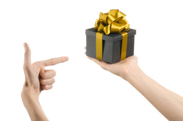 hand holding a gift wrapped in a black box with gold ribbon