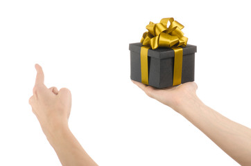 hand holding a gift wrapped in a black box with gold ribbon