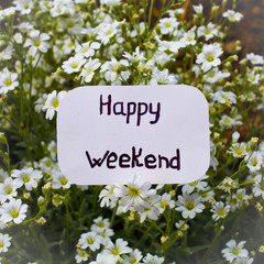 A label with Happy Weekend on it and white flowers in the backgr