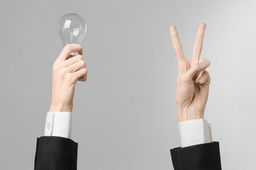 man's hand in a black suit holding a light bulb in studio 