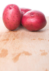 Red potato on wooden surface