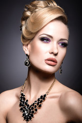 Beautiful girl with bright makeup and evening hairstyle. Picture taken in the studio on a gray background.