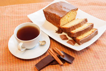 Cup of tea and cake with glaze of chocolate and spices  in the w