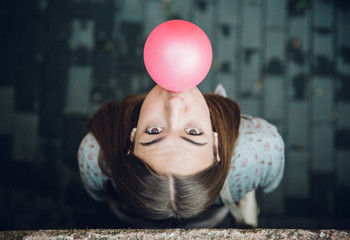 Young teenage girl blowing pink bubble gum
