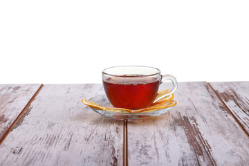 Glass cup with tea and a lemon on a glass saucer isolated