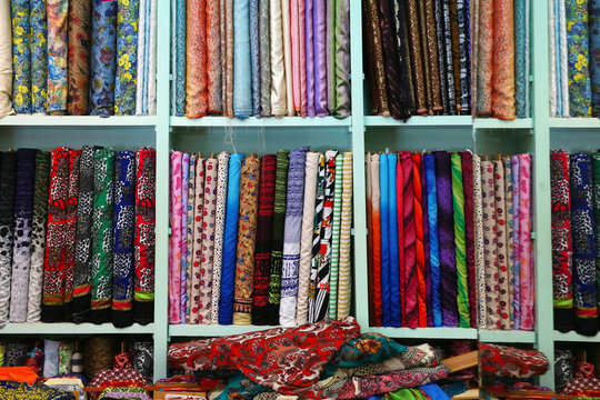 A variety of different bolt of  fabric displayed on shelves