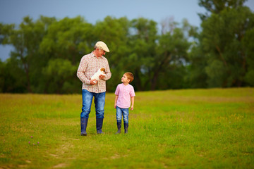 Fototapeta premium grandfather and grandson walking with puppy in hands