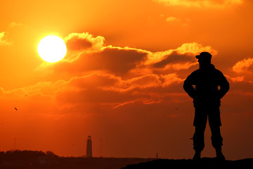 Silhouette shot of soldier holding gun with colorful sky 