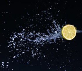 Half a lime falling into the water isolated on a black 
