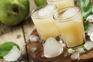 Pear fresh juice with ice in a heart-shaped and pear on a wooden