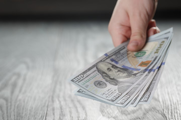 young female hands count dollar bills on wood table, closeup