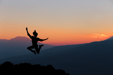 Happy woman jumping against beautiful sunset