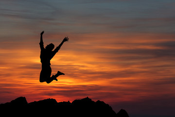 Happy woman jumping against beautiful sunset. Freedom concept.