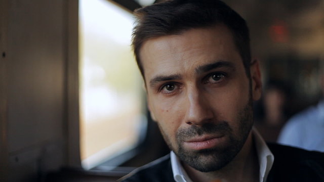 young man takes off glasses and looking at the camera