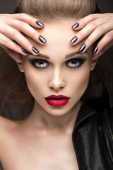 Beautiful girl in leather jacket with bright makeup and manicure "Cat's Eye". Beauty face. Nail Design. Picture taken in the studio on a black background.
