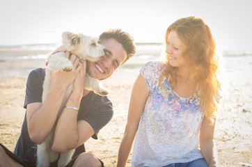 Couple in love playing with ther dog at the beach