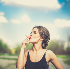 Pretty woman in black dress smoking sigarette outdoor