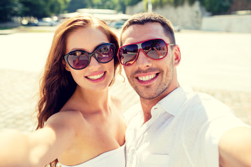 smiling couple wearing sunglasses making selfie