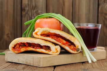 Two pieces of pizza calzone with glass of red wine, fresh scalli
