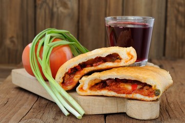 Two pieces of pizza calzone with glass of red wine, fresh scalli