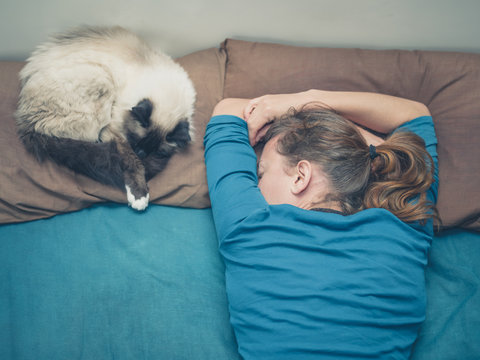 Woman sleeping in bed with cat