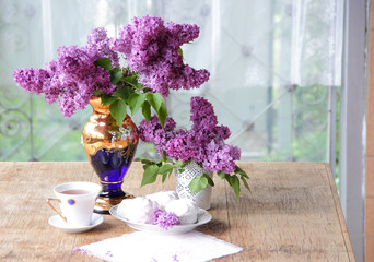 Tea in a porcelain cup, a zephyr and a lilac bouquet in a beauti