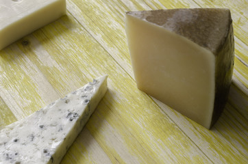 Spanish Manchego cheese, gruyere, gorgonzola over yellow wood.