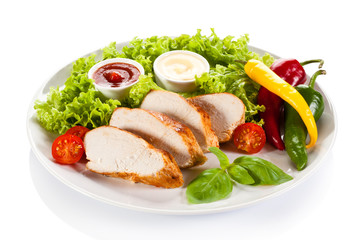 Roast chicken fillet and vegetables on white background
