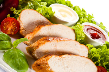 Roast chicken fillet and vegetables on white background