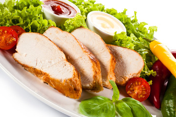 Roast chicken fillet and vegetables on white background