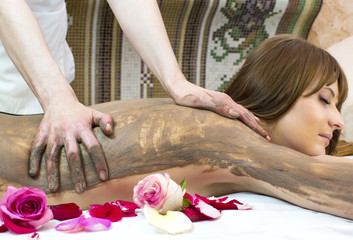 Obraz na płótnie Canvas Young girl doing a clay massage procedure