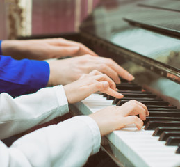 Woman teaching little girl to play the piano.