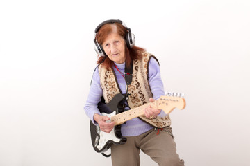 Funny elderly lady playing electric guitar.