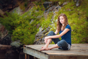 teen girl sitting on a dock deep in thought