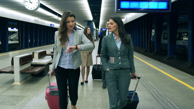 Businesspeople walking with luggage on the station, steadycam shot
