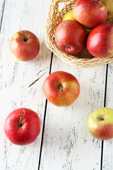 Apples in basket on white wooden background