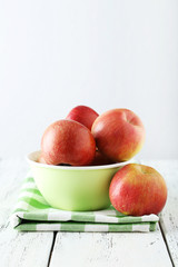 Apples in bowl on white wooden background