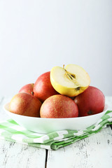 Apples in bowl on white wooden background