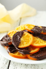 Delicious slices of orange coated chocolate on plate 