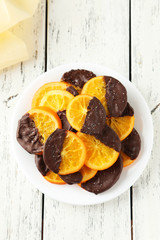 Delicious slices of orange coated chocolate on plate 