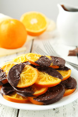 Delicious slices of orange coated chocolate on plate 