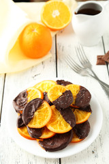Delicious slices of orange coated chocolate on plate 