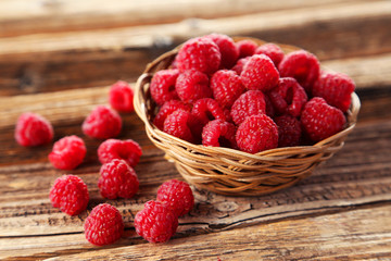 Raspberries in basket on brown wooden background