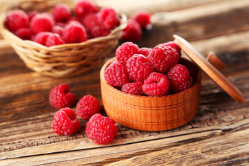 Raspberries in bowl on brown wooden background